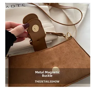 Dettaglio della chiusura magnetica in metallo su borsa a spalla in pelle scamosciata