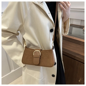 Dettaglio borsa baguette marrone con fibbia a U dorata e texture in pelle opaca fine
