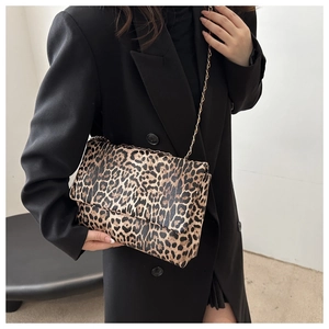 Detail der trendigen Leopard-Schultertasche mit Goldkette auf einem schwarzen Blazer