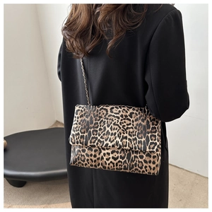 Close-up of leopard print crossbody bag with metal chain strap on model's shoulder