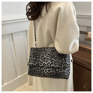 Detail der Schultertasche mit Leopardenmuster und Metallkette getragen von Model