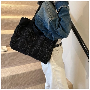 Détail du sac cabas en denim noir avec lettrage GENTLE YOUTH et bords effilochés