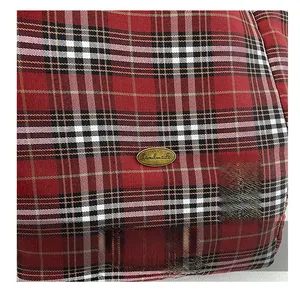 Close-up of red and black plaid canvas fabric with an oval bronze handmade metal plate