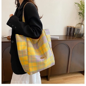 Detail of a large plaid canvas tote bag with a handmade leather tag and retro design