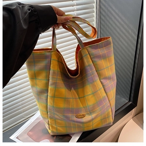 Detail of colorful plaid tote bag featuring handmade label and vibrant orange lining