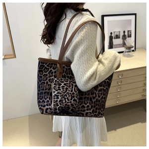 Lifestyle shot of large leopard print tote bag with brown leather straps and small pouch