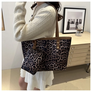 Detail of leopard print tote bag featuring leather handles and matching small zip pouch