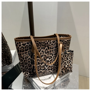 Close-up of leopard print tote bag set with matching small zipper pouch on books
