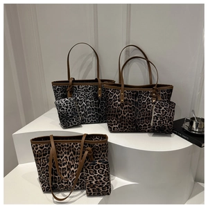 Three leopard print tote bags with matching pouches on minimalist geometric stands