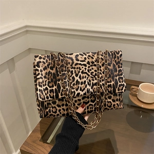 Stilvolle Schultertasche mit Leopardenmuster und goldener Kette auf einem Holztisch