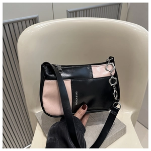 Detail of black and pink patchwork underarm bag with silver flower chain on a white chair