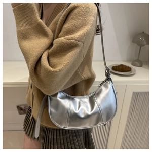 Detail of silver metallic crescent bag with adjustable strap on model's shoulder