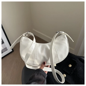 Detail view of white crescent moon bag with textured leather and adjustable strap