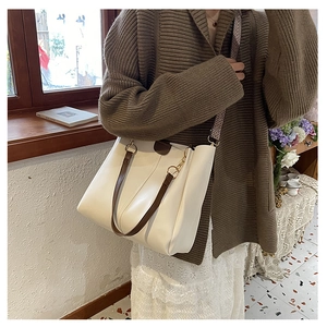 Detail of cream tote bag featuring brown straps and geometric pattern wide shoulder strap