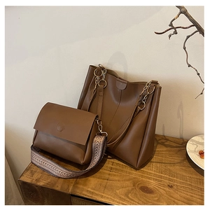 Detail of dark brown tote bag set with wide woven strap on a vintage wooden surface