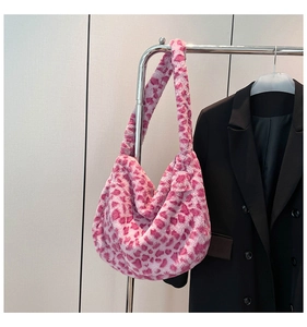 Borsa hobo in peluche leopardata rosa appesa accanto a un blazer nero per lo stile