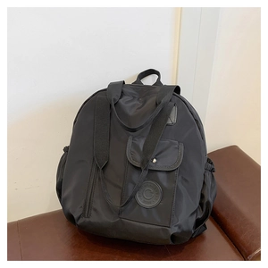 Close-up of black nylon backpack with circular brand patch and waterproof fabric texture