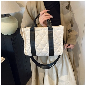 Detailed view of cream quilted nylon tote bag with contrasting black handles and shoulder strap