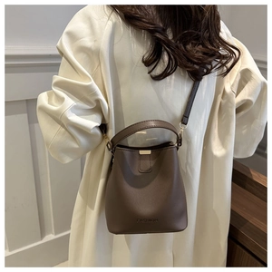 Detail of a dark brown PU leather bucket bag with FASHION logo and gold hardware