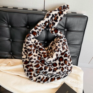 Sac à épaule en fausse fourrure léopard posé élégamment sur un canapé en cuir noir