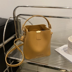 Modern ginger yellow PU leather bucket bag with top handle and golden hardware details