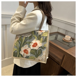 Detalle de un bolso tote grande de lino con bordado floral 3D y asas de color beige