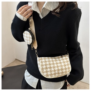 Chic houndstooth crossbody bag featuring a round coin purse and wide fabric shoulder strap