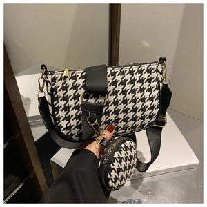 Detail of black and white houndstooth crossbody bag with a round mini coin purse and gold zipper