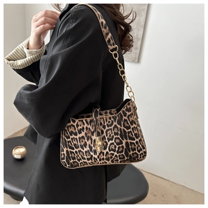 Detail of leopard print underarm bag featuring a gold chain strap and metal swivel lock