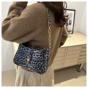 Detail of leopard print underarm bag with gold chain strap and magnetic snap closure
