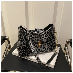 Detail of leopard print shoulder bag with gold metal buckle and chain strap on book