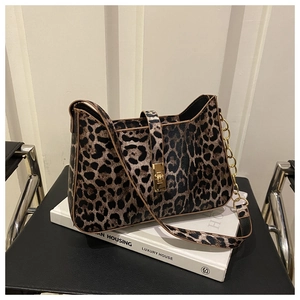 Close-up of leopard print shoulder bag with gold twist lock and chain strap on books