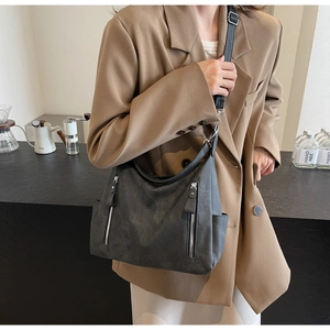 Détail du sac bandoulière gris à texture mate et doubles poches zippées verticales