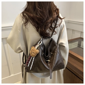 Detail of dark brown vintage faux leather tote with cute bear charm and striped strap