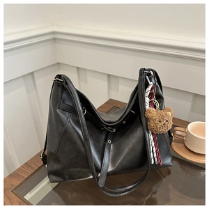 Detail of black PU leather tote bag with brown plush bear charm and plaid scarf