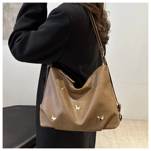 Close-up of brown PU leather tote bag featuring gold butterfly ornaments and side straps