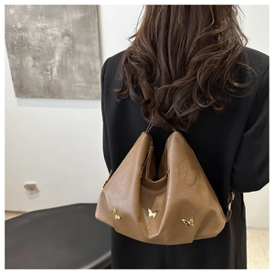 Brown soft leather backpack with gold butterfly accents worn on black blazer