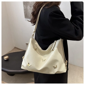 Detail of cream pleated shoulder bag with golden butterfly buckles on textured PU leather