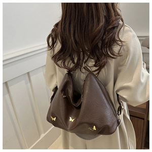 Detailed view of deep brown tote bag with golden butterfly charms and shoulder strap