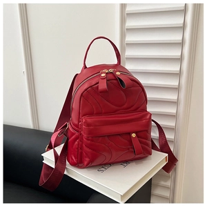 Detail of a red quilted leather mini backpack with gold zippers on white books