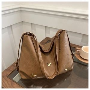Detail of caramel tote bag showing lychee grain texture and golden butterfly hardware