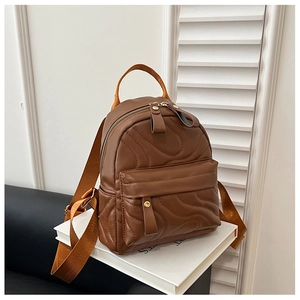 Detail of wave quilted brown PU leather backpack with gold buckle and woven strap