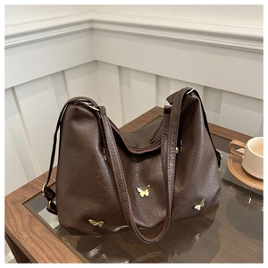 Detail of vintage brown tote bag featuring golden butterfly charms and soft textured leather