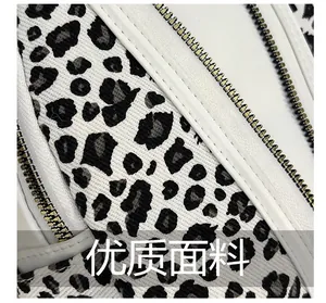 Detailed macro view of gray leopard print fabric with precise white leather edge zippers