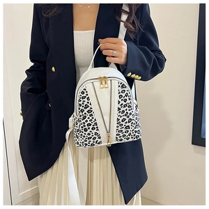 Detail of leopard print panel and gold zippers on a stylish white mini backpack