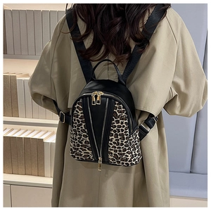 Close-up of leopard print backpack with gold zippers worn over a khaki trench coat