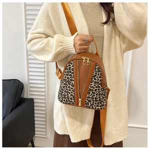 Detail of trendy leopard print backpack with brown leather stitching and golden zippers