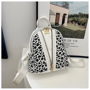 Detail of leopard print panels and gold zippers on a stylish white mini backpack