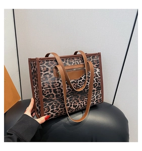 Close-up of leopard print tote bag featuring a metal zipper pocket and dark brown handles
