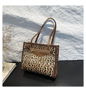 Detail of leopard print tote bag with brown leather trim and golden zipper pocket